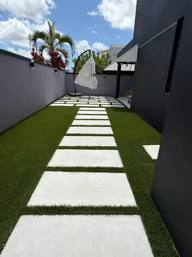 Patio contemporáneo con losas claras y grama artificial