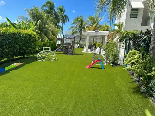 Jardín residencial con grama artificial, columpios y juegos