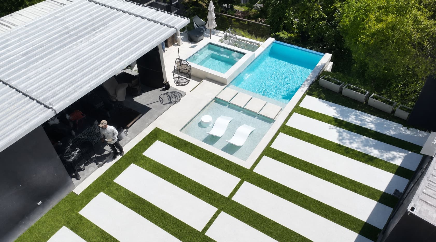 Área exterior con piscina, patios de concreto y franjas de grama artificial