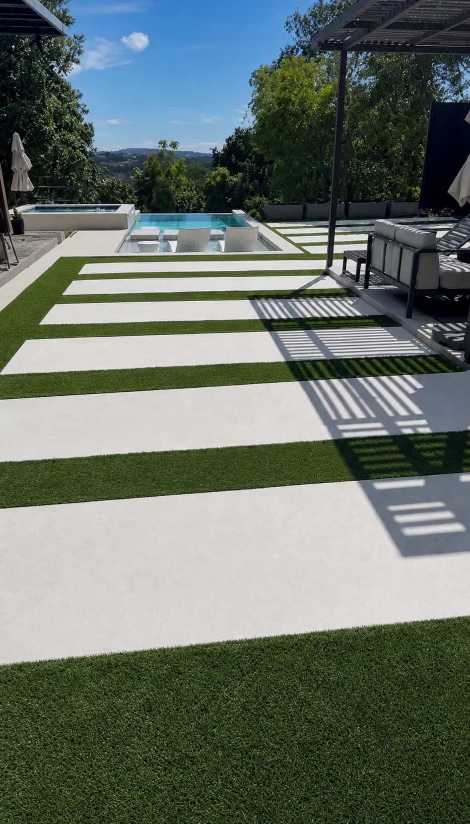 Patio junto a piscina con franjas de grama artificial