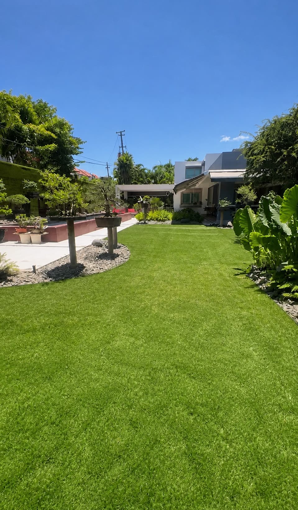 Jardín residencial amplio con grama artificial y vegetación