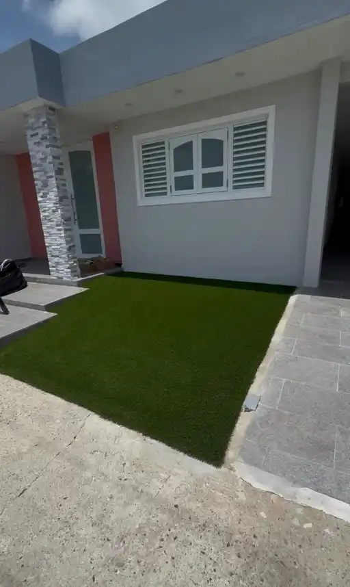 Patio residencial con grama artificial frente a la vivienda